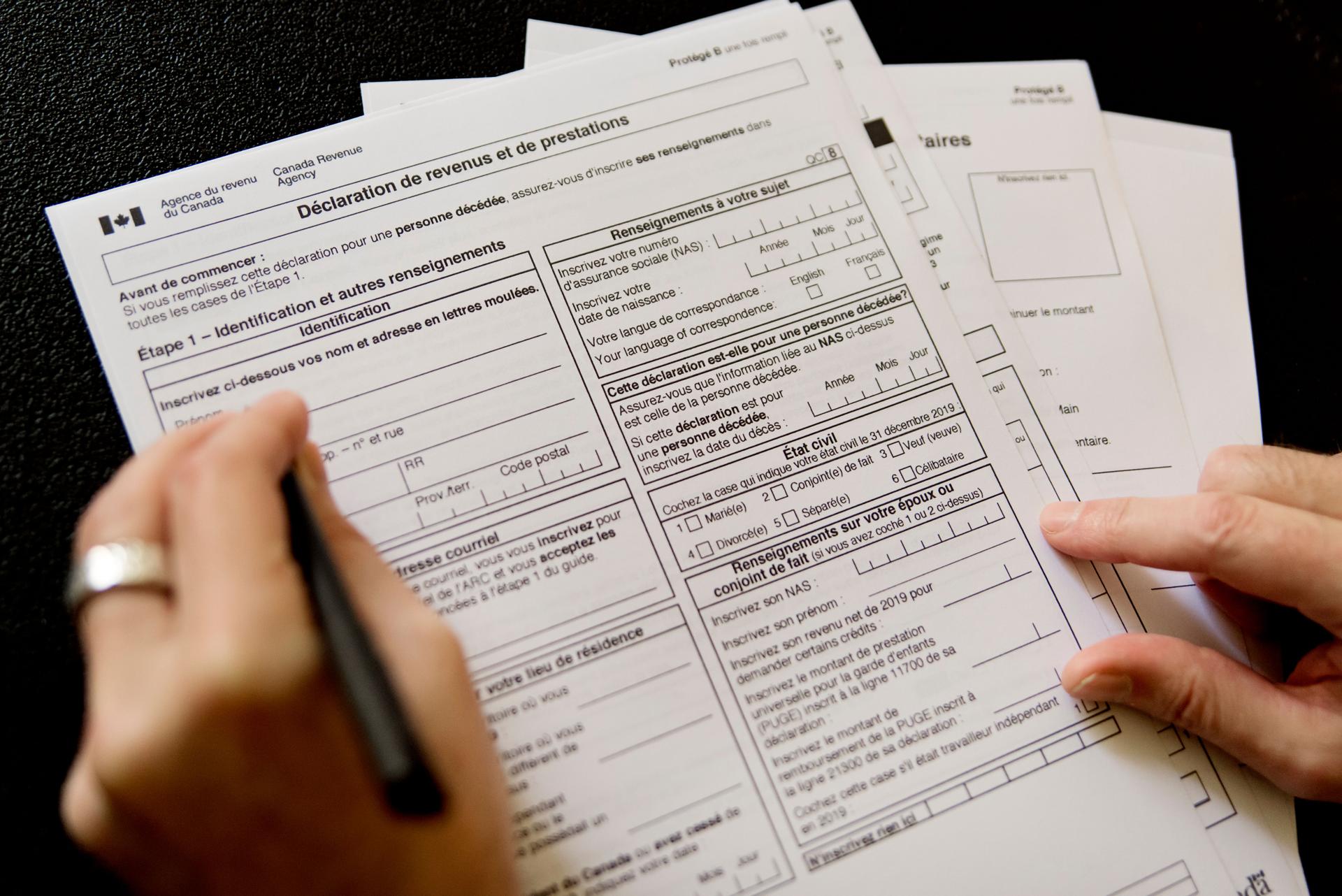 Man hand filling french canadian tax papers.